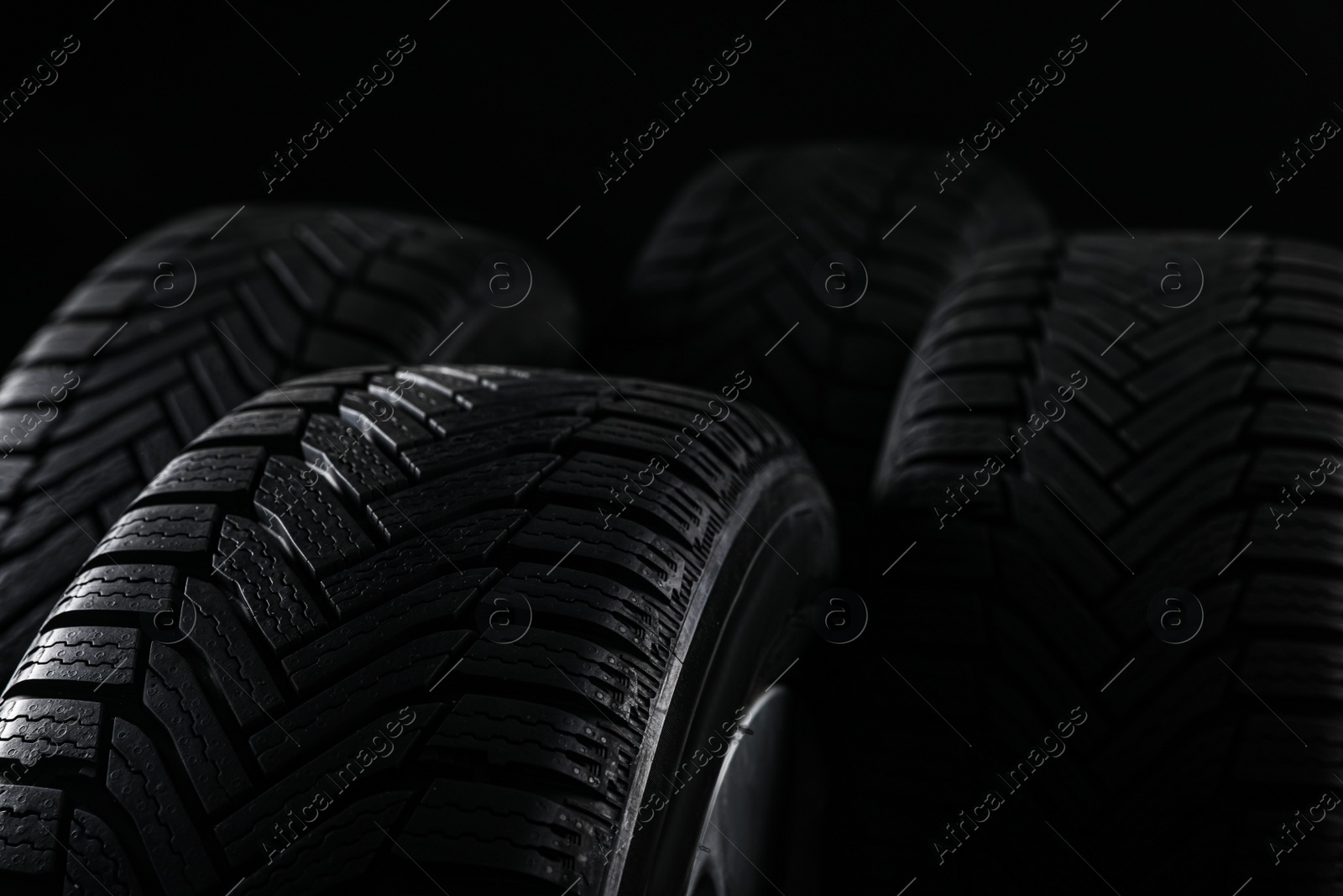 Photo of Set of wheels with winter tires on black background, closeup. Space for text