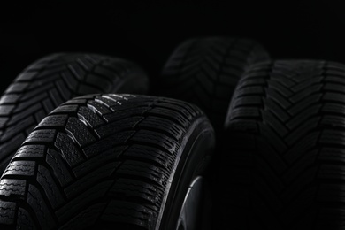 Set of wheels with winter tires on black background, closeup. Space for text