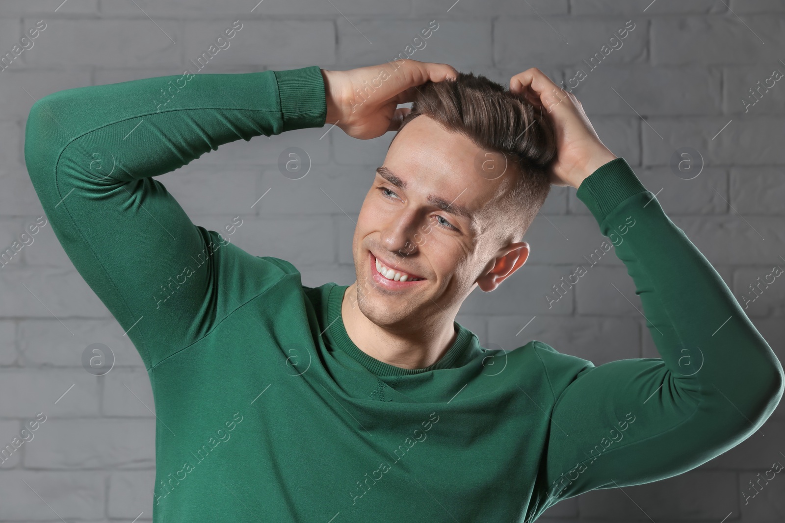 Photo of Portrait of young man with beautiful hair on brick wall background