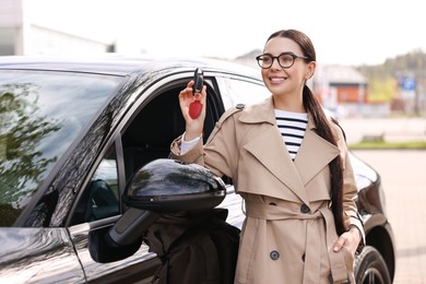 Woman holding car flip key near her vehicle outdoors