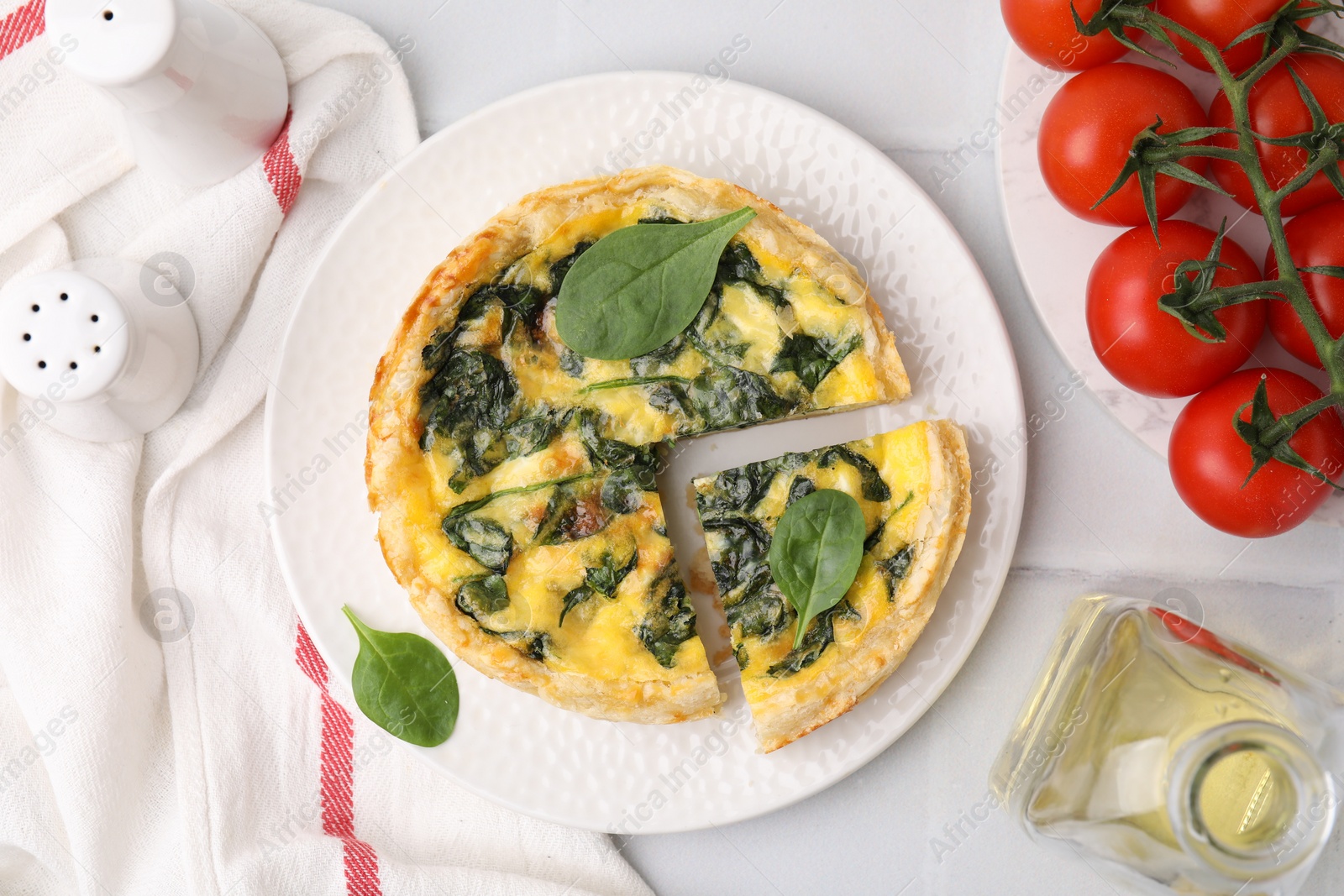 Photo of Delicious pie with spinach on white tiled table, flat lay