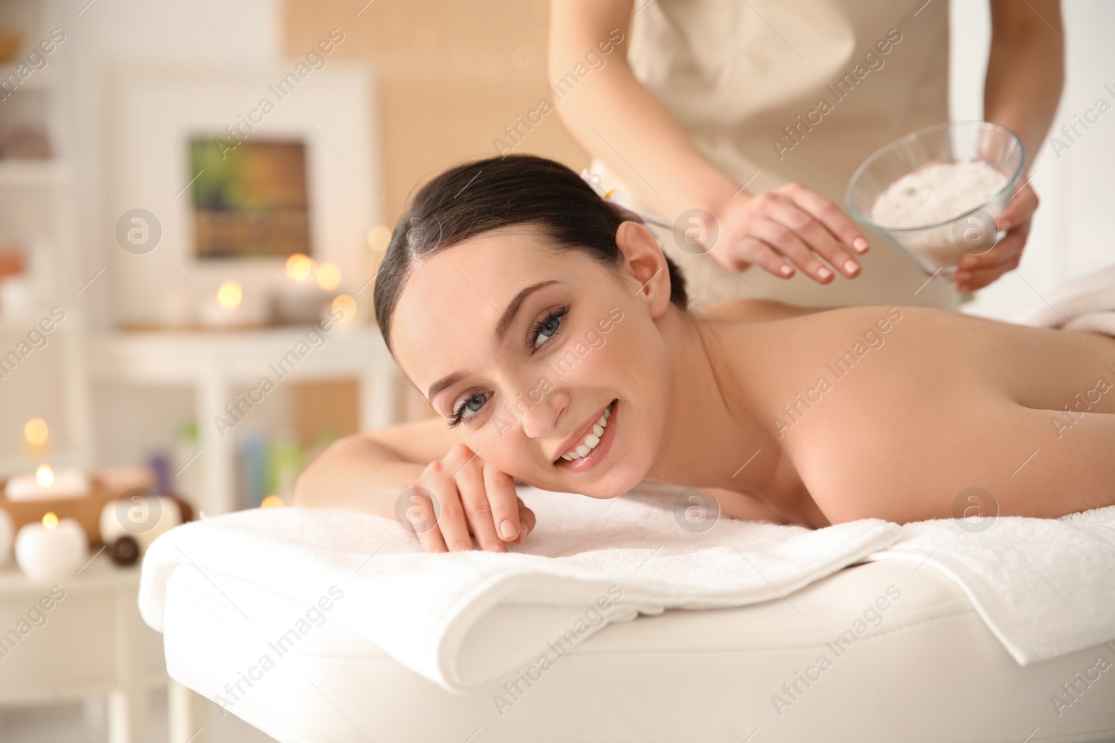 Photo of Beautiful young woman having massage with body scrub in spa salon