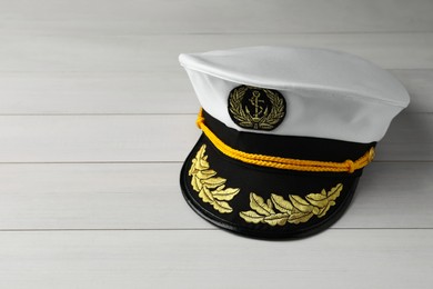 Photo of Peaked cap with accessories on white wooden background, space for text