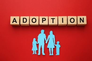 Photo of Family figure and word Adoption made of cubes on red background, flat lay