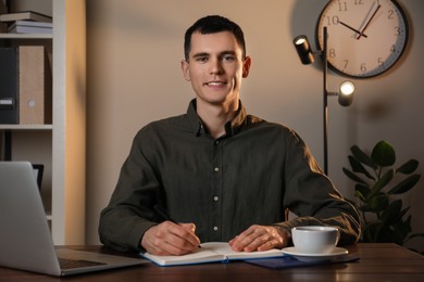 Man taking notes at wooden table in office