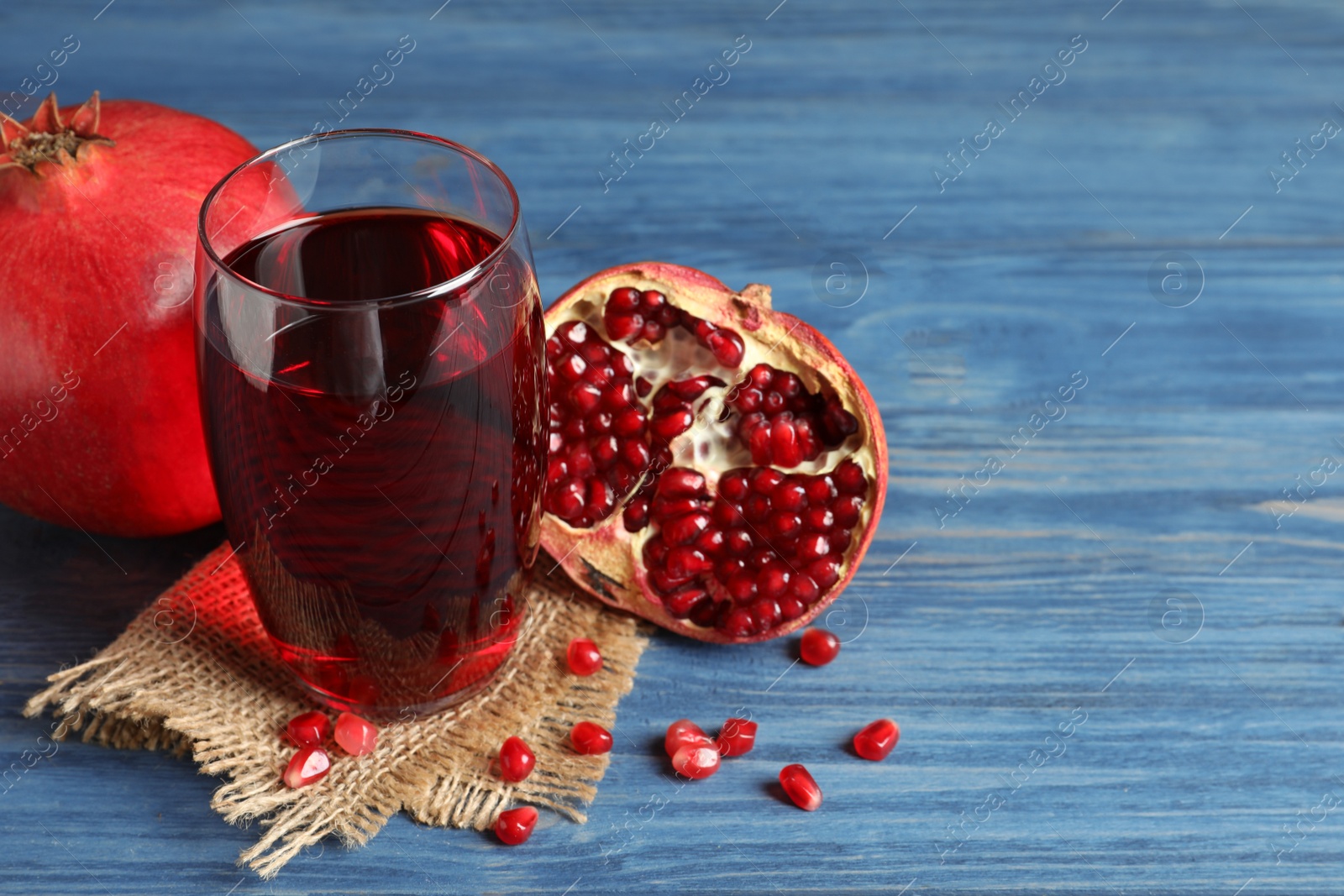 Photo of Glass of pomegranate juice and fresh fruits on wooden background, space for text