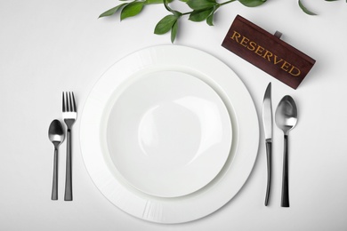 Photo of Elegant table setting with RESERVED sign on white background, top view
