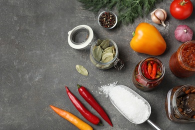 Photo of Flat lay composition with products and jars of pickled vegetables on grey table