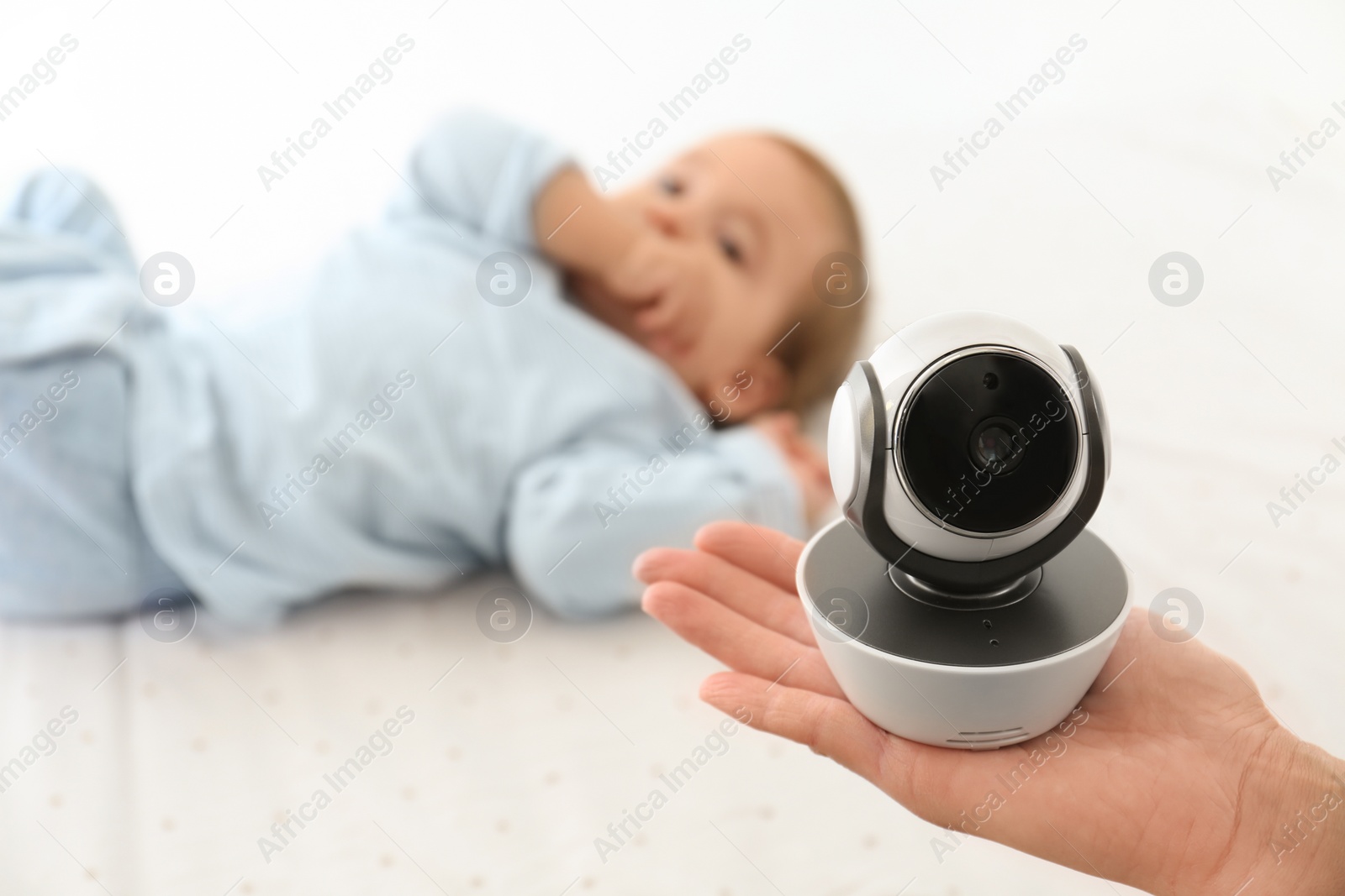 Photo of Woman holding baby camera near child on bed. Video nanny