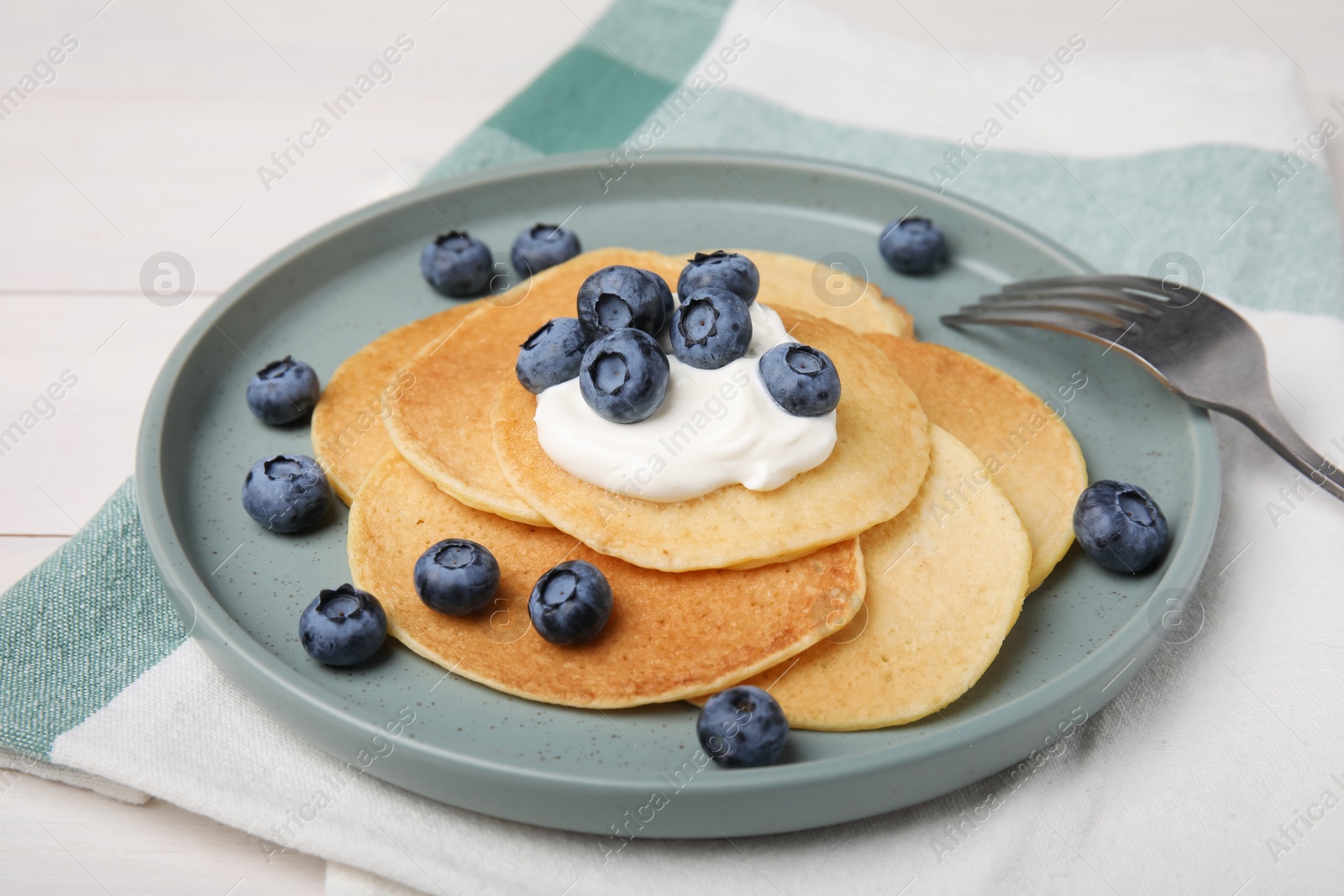 Photo of Tasty pancakes with natural yogurt and blueberries on white wooden table
