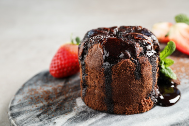 Photo of Delicious warm chocolate lava cake on marble board, closeup