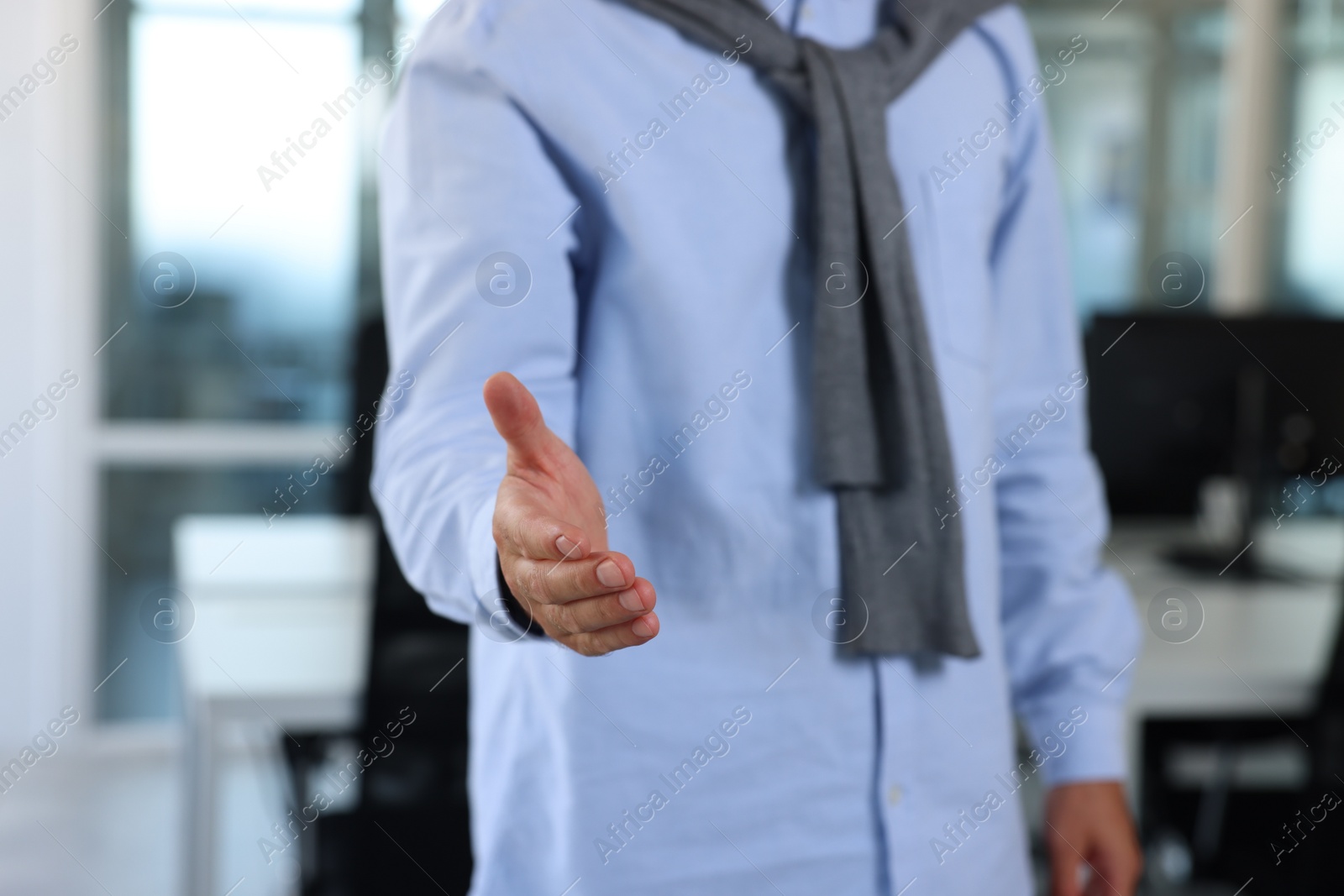 Photo of Man welcoming and offering handshake indoors, closeup