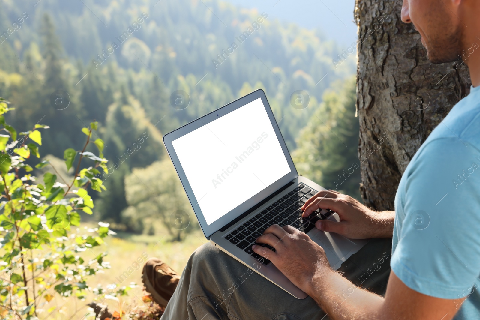 Photo of Man working on laptop outdoors surrounded by beautiful nature, closeup. Space for text