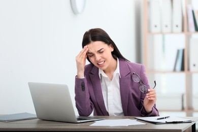 Photo of Woman suffering from migraine at workplace in office