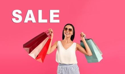 Beautiful young woman with paper shopping bags and word SALE on pink background