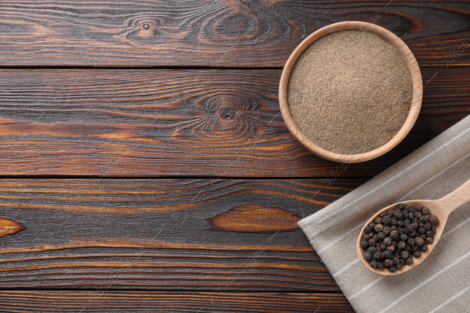 Photo of Ground pepper and corns on wooden table, flat lay. Space for text