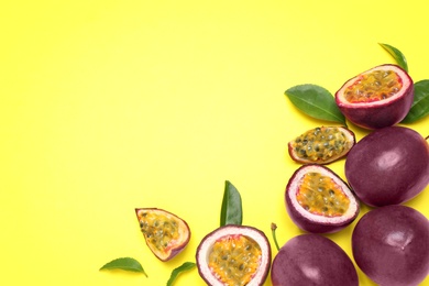 Fresh ripe passion fruits (maracuyas) with green leaves on yellow background, flat lay. Space for text