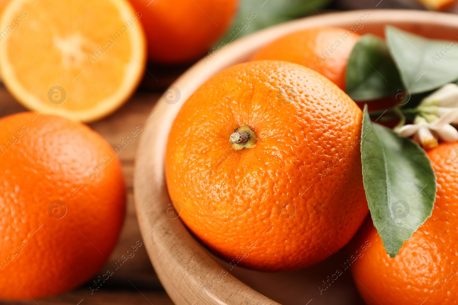 Photo of Delicious ripe oranges in wooden bowl, closeup