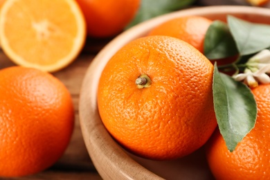 Delicious ripe oranges in wooden bowl, closeup