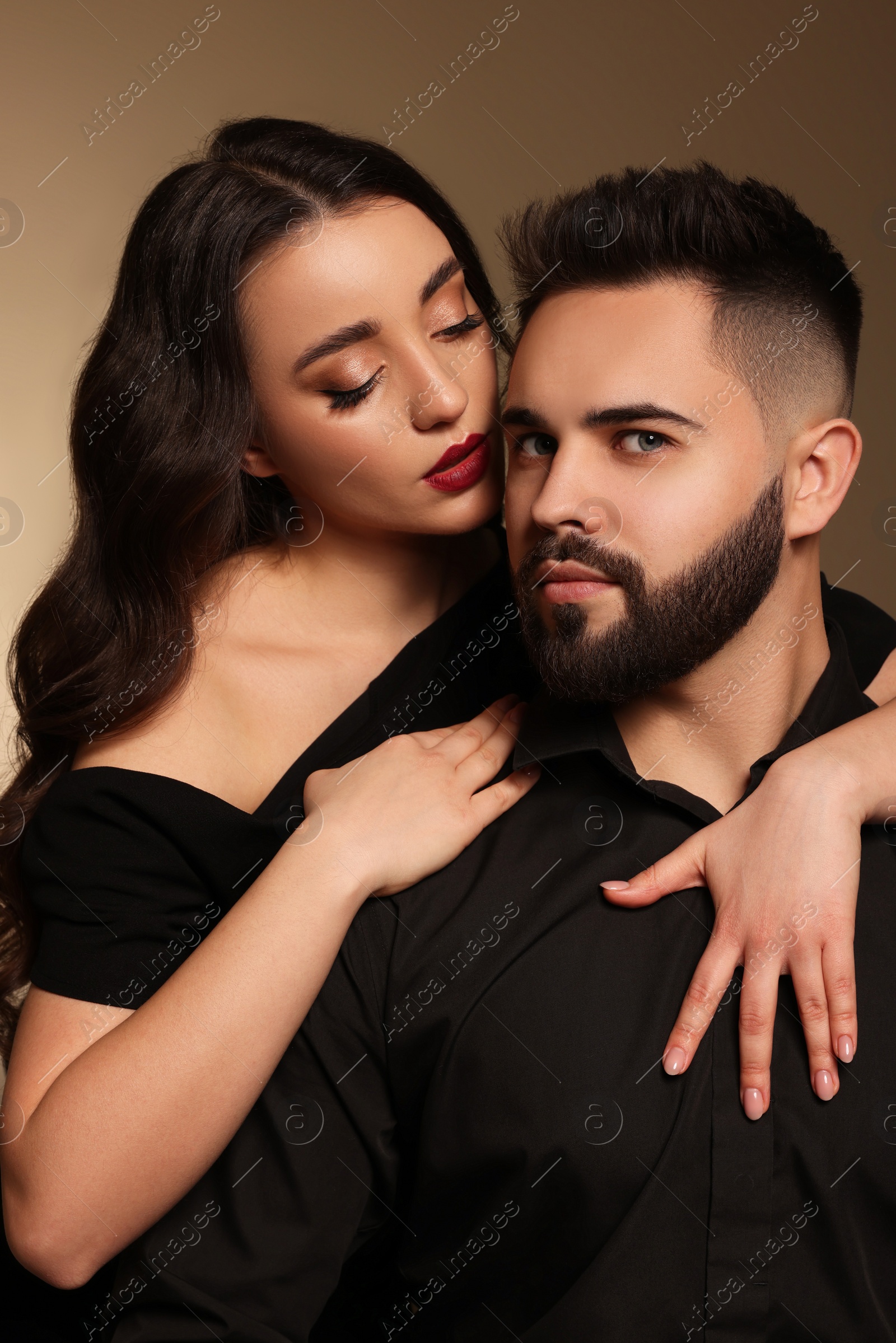 Photo of Handsome bearded man with sexy lady on light brown background