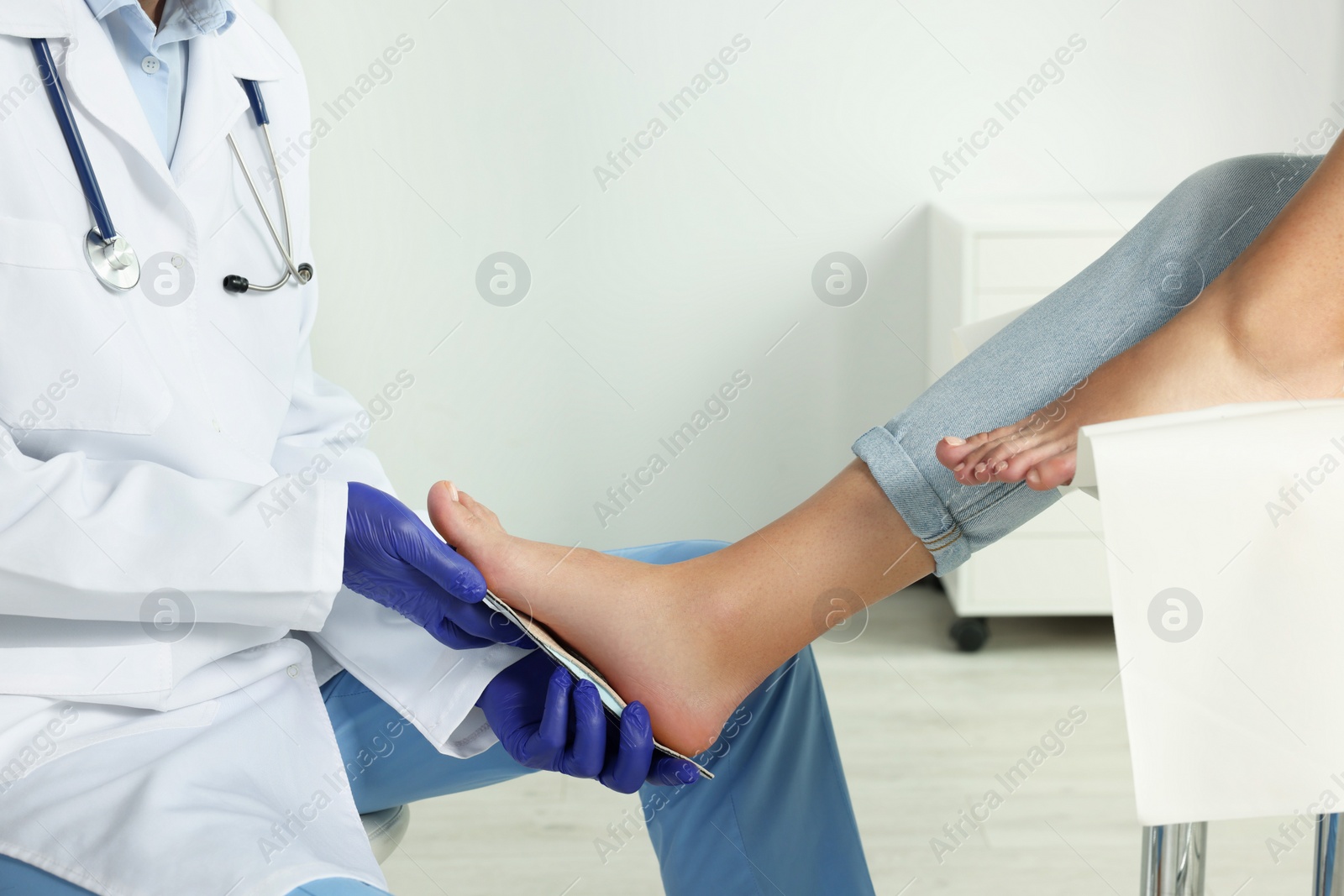 Photo of Male orthopedist fitting insole to patient's foot in hospital, closeup