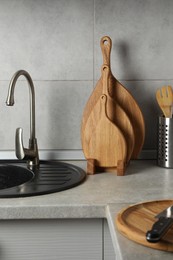 Photo of Wooden cutting boards and other cooking utensils on light grey countertop in kitchen