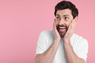 Portrait of happy surprised man on pink background, space for text