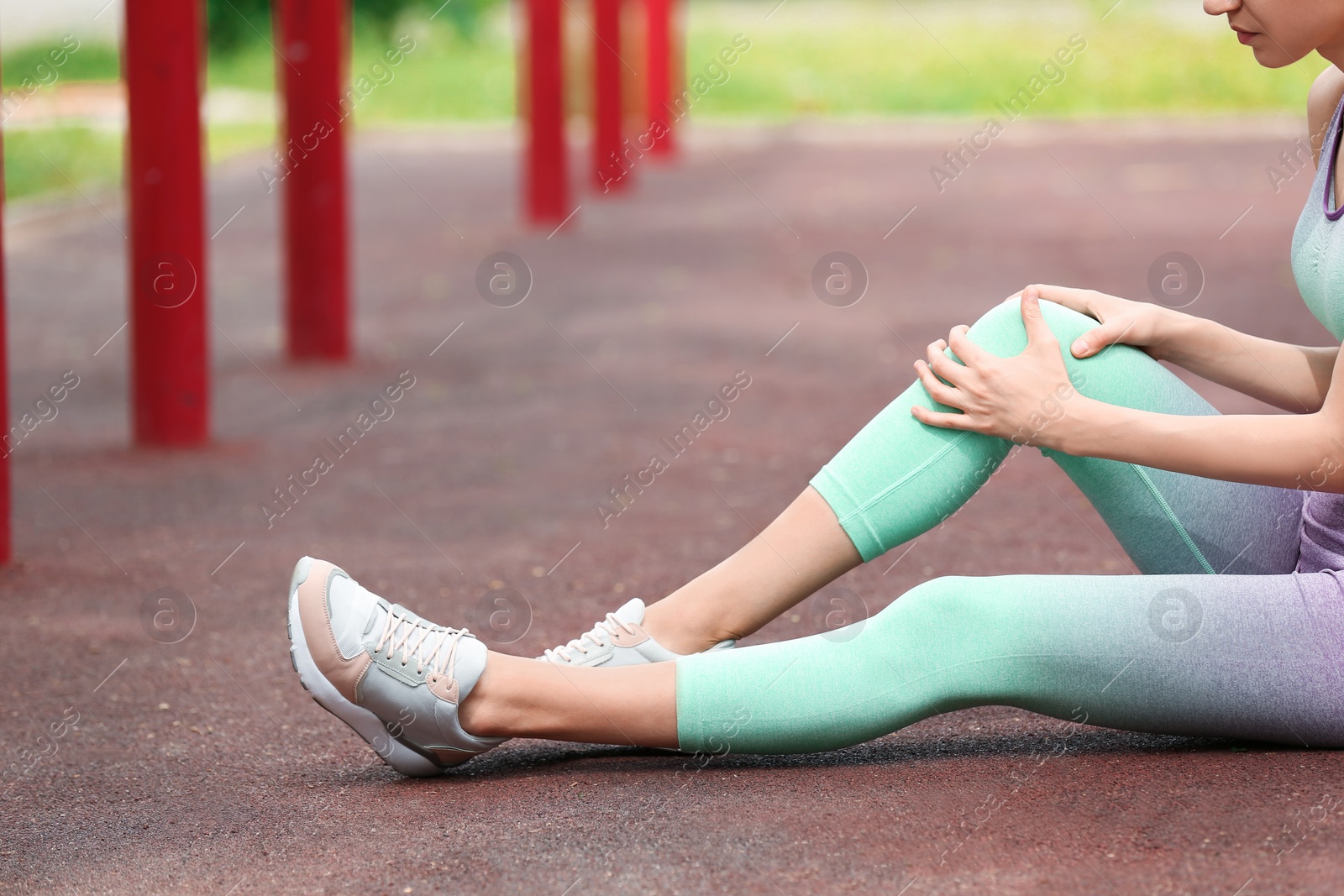 Photo of Young woman suffering from knee pain on sports ground, closeup