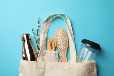 Photo of Bag with eco friendly products on light blue background, flat lay. Conscious consumption