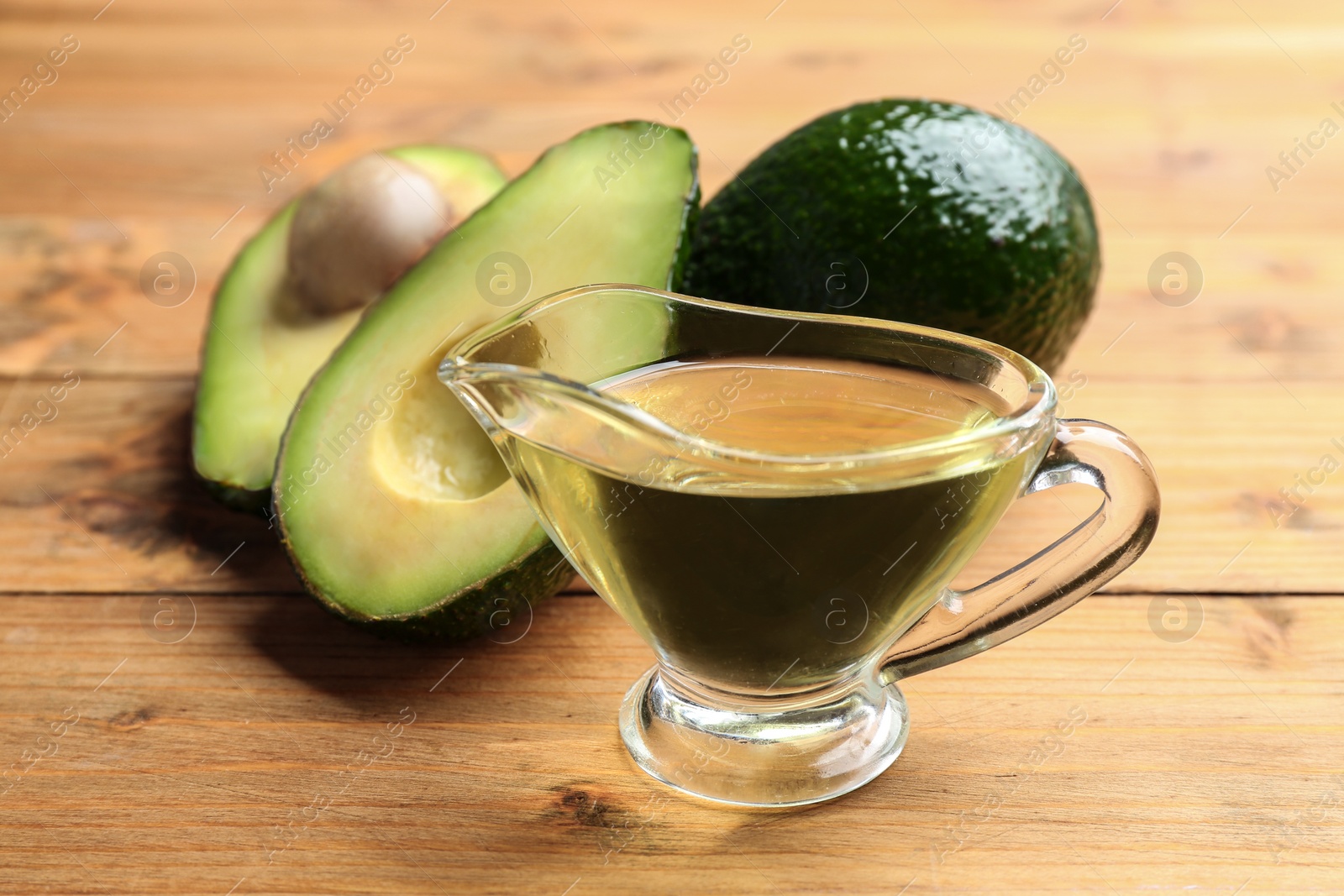 Photo of Composition with natural oil and avocados on wooden background