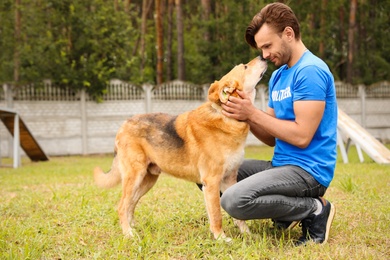 Male volunteer with homeless dog at animal shelter outdoors