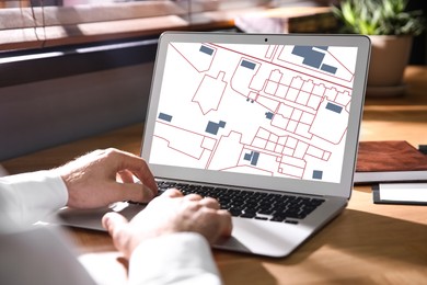 Image of Man analyzing cadastral map on laptop at table, closeup 