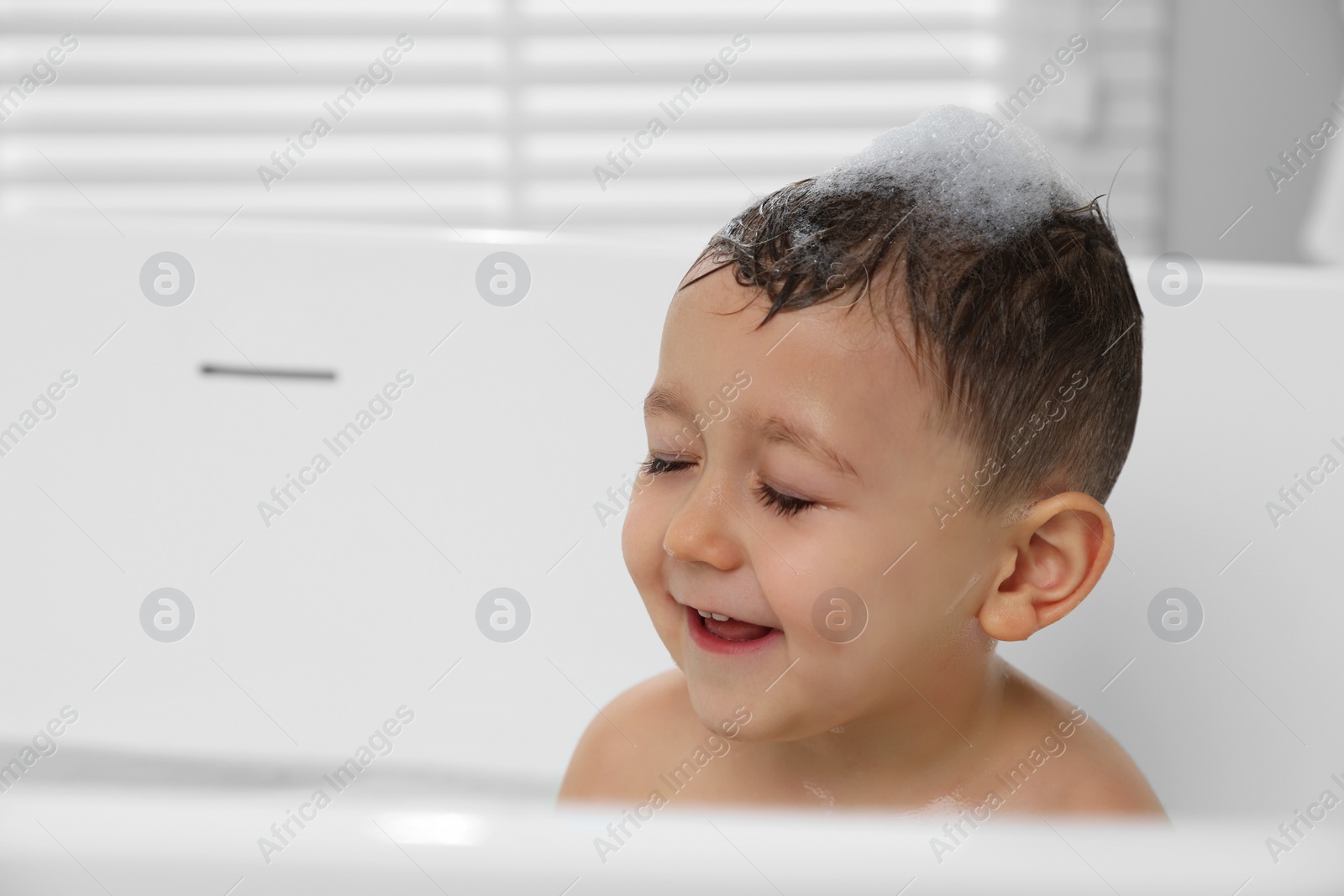 Photo of Cute little boy washing hair with shampoo in bathroom. Space for text