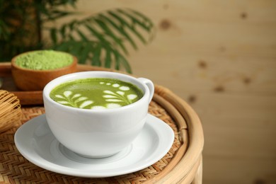 Photo of Delicious matcha latte in cup on coffee table indoors. Space for text