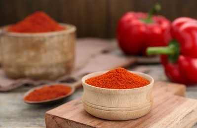 Photo of Bowl with aromatic paprika powder on wooden table