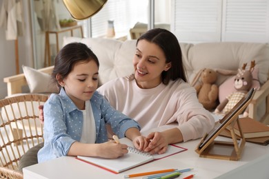 Mother helping her daughter with homework using tablet at home