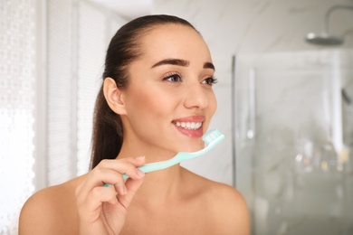 Photo of Woman holding toothbrush with paste in bathroom