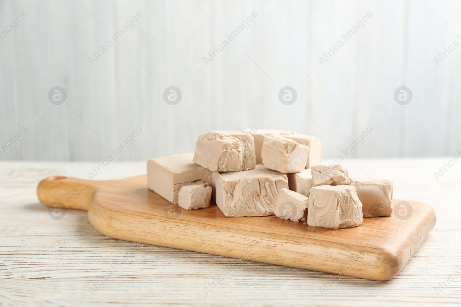 Photo of Pieces of compressed yeast on white wooden table