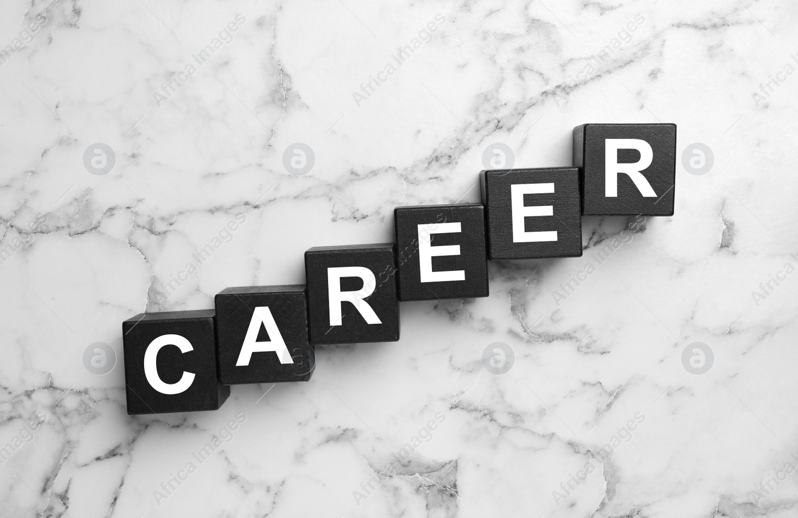 Photo of Black cubes with word CAREER on white marble background, flat lay