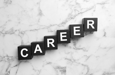 Black cubes with word CAREER on white marble background, flat lay