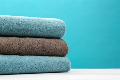 Photo of Stack of soft clean towels on table against color background. Space for text