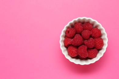 Photo of Bowl of fresh delicious raspberries on pink background, top view. Space for text