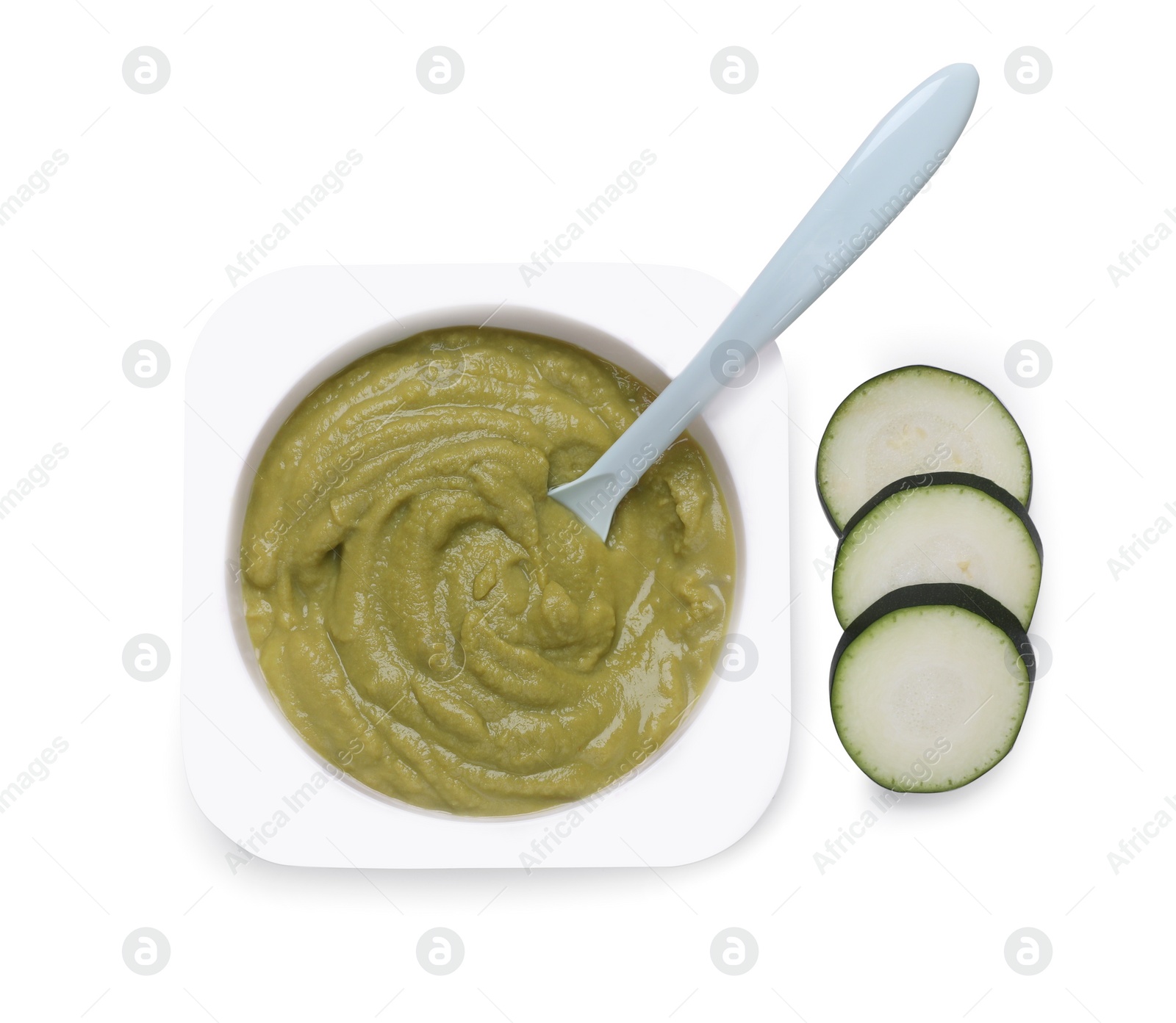 Photo of Container with healthy baby food, spoon and zucchini isolated on white, top view