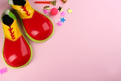 Photo of Flat lay composition with clown shoes and accessories on pink background. Space for text