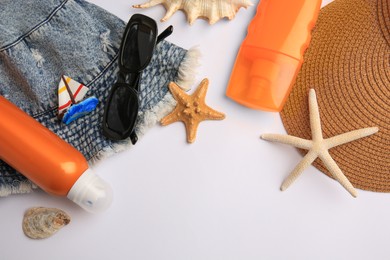 Flat lay composition with bottles of sunscreen on white background. Space for text