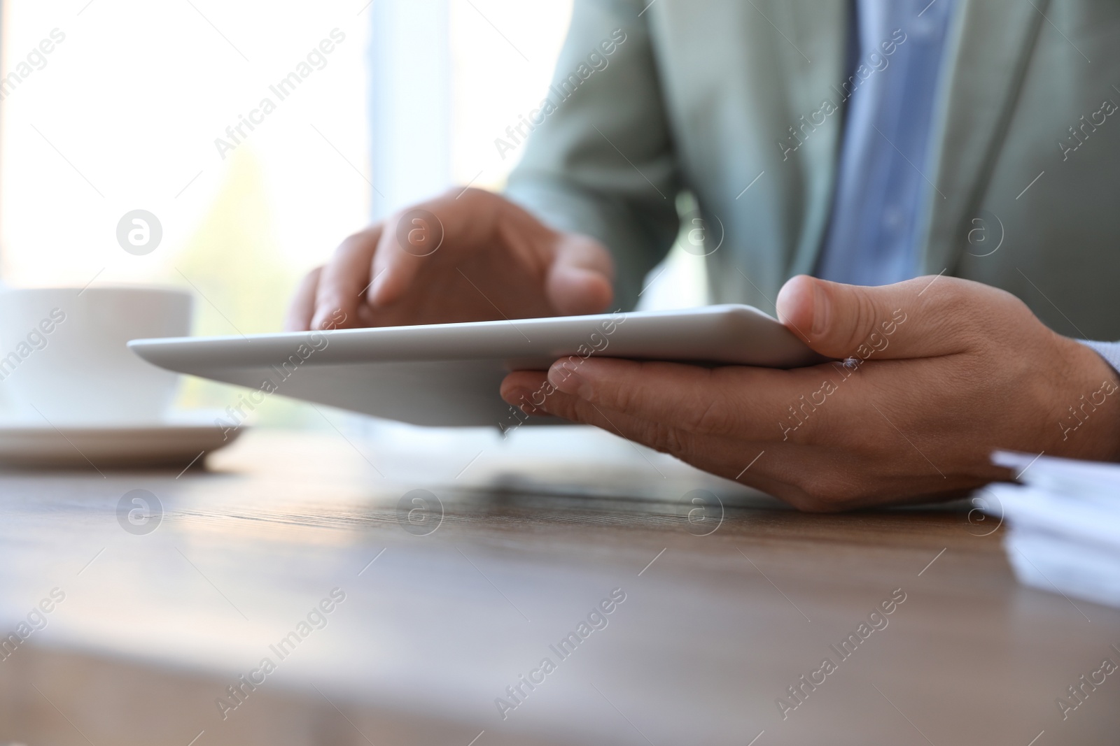 Photo of Businessman working with modern tablet at wooden table in office, closeup