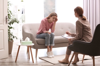 Photo of Psychotherapist working with young woman in light office