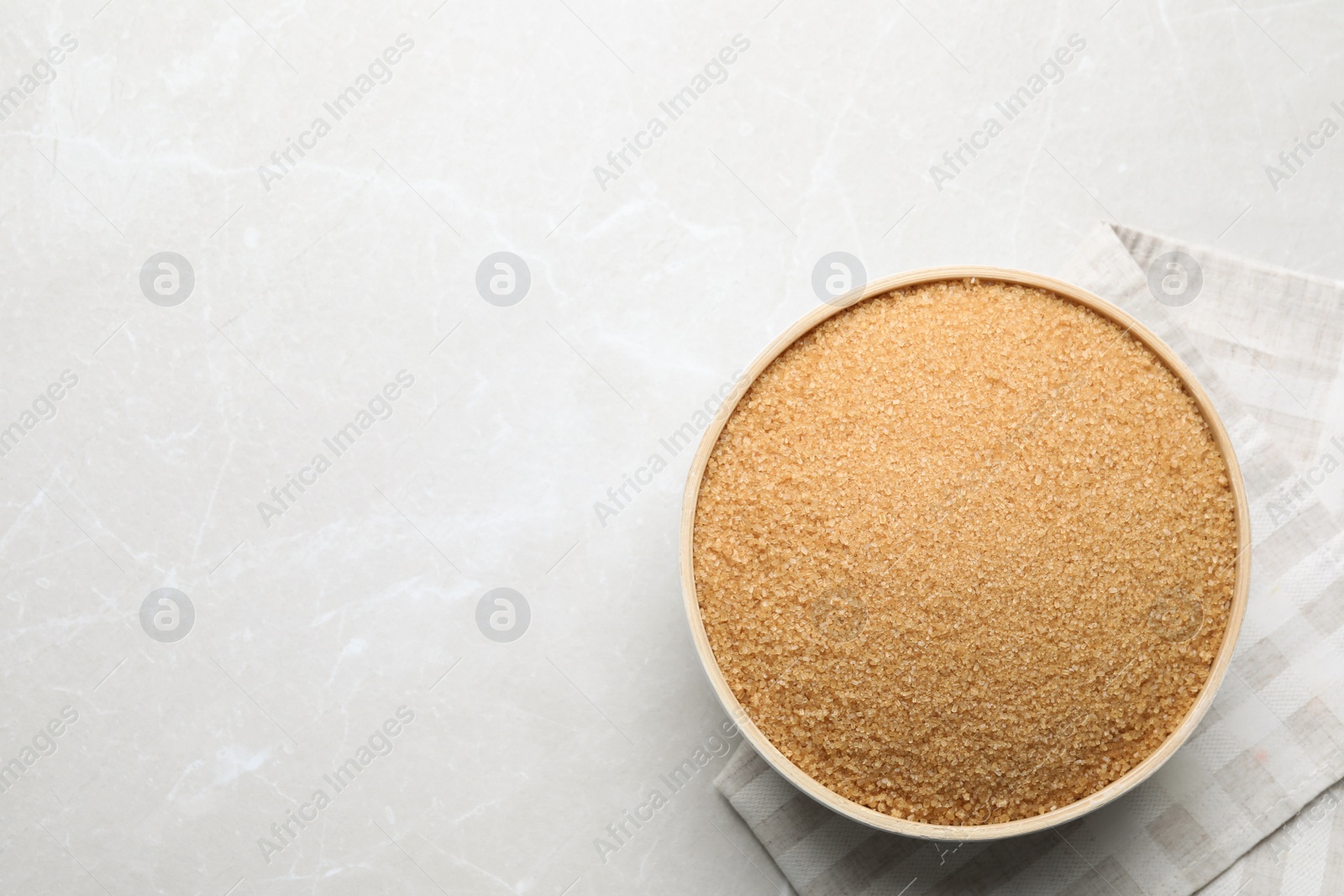 Photo of Brown sugar in bowl on light grey table, top view. Space for text