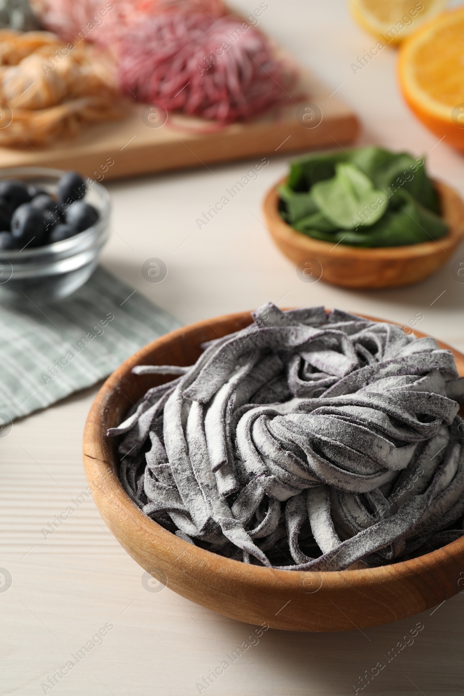 Photo of Rolled pasta painted with food coloring and ingredients on white wooden table