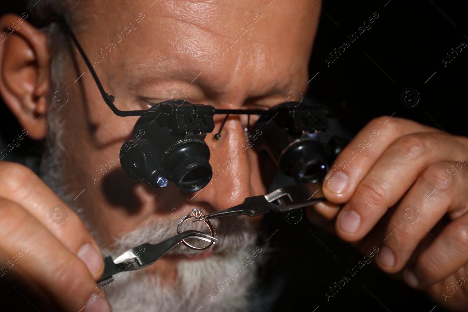 Photo of Male jeweler evaluating diamond ring in workshop, closeup view